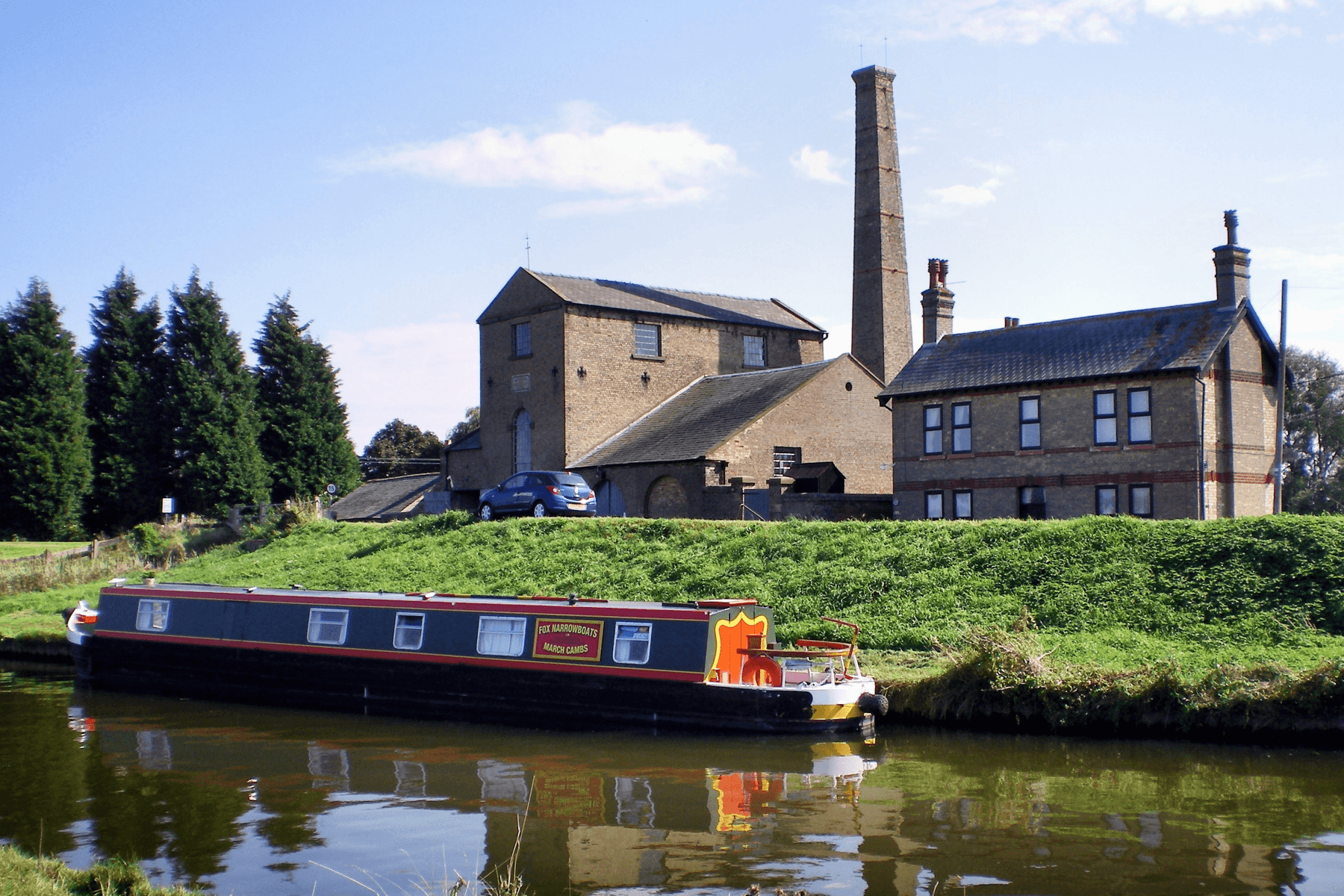 Things to do in East Cambridgeshire - Stretham Old Engine- photo of exterior from water with barge on the river